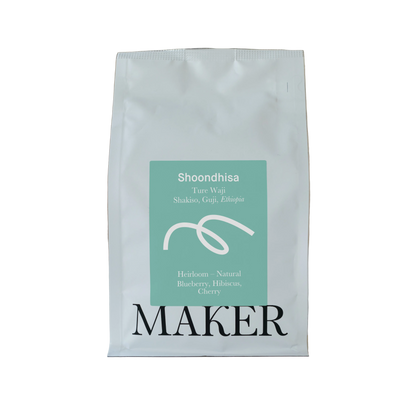 White coffee bag with teal label featuring 'Shoondhisa' and 'Maker' on a beige background