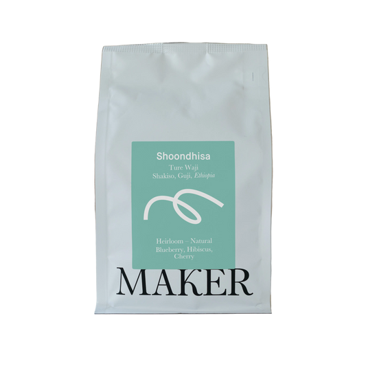 White coffee bag with teal label featuring 'Shoondhisa' and 'Maker' on a beige background